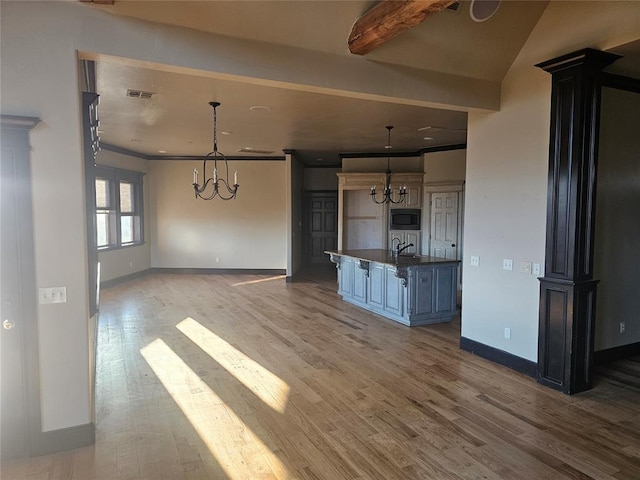 kitchen featuring pendant lighting, a center island with sink, an inviting chandelier, and built in microwave