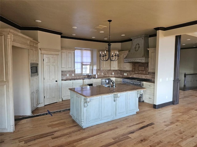 kitchen featuring stainless steel appliances, pendant lighting, a kitchen island, custom range hood, and light wood-type flooring