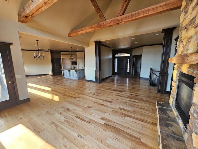 unfurnished living room featuring a notable chandelier, beam ceiling, light wood-type flooring, and high vaulted ceiling