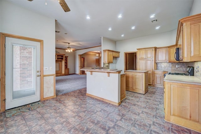 kitchen with a kitchen breakfast bar, a center island, backsplash, and light brown cabinetry