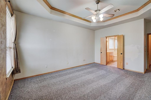 unfurnished bedroom featuring light carpet, multiple windows, a tray ceiling, and ceiling fan