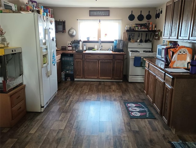 kitchen featuring dark hardwood / wood-style flooring, sink, dark brown cabinets, and white appliances