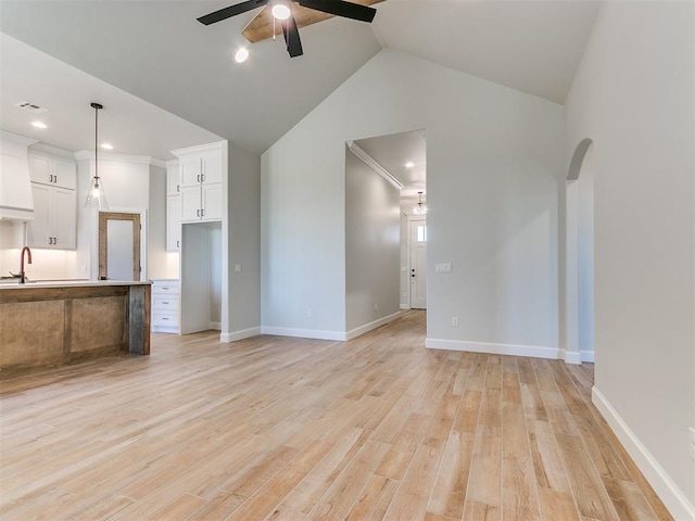 unfurnished living room featuring crown molding, sink, vaulted ceiling, ceiling fan, and light hardwood / wood-style floors