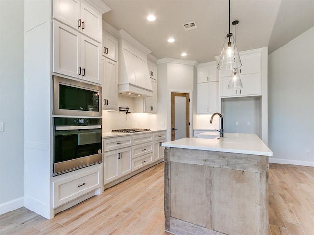 kitchen with sink, white cabinetry, a kitchen island with sink, and appliances with stainless steel finishes