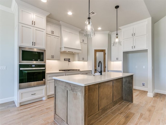 kitchen with a center island with sink, white cabinetry, and appliances with stainless steel finishes