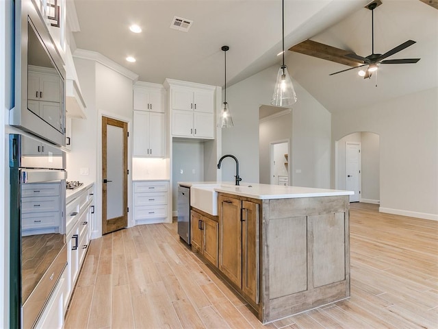 kitchen featuring vaulted ceiling, ceiling fan, sink, a center island with sink, and white cabinetry