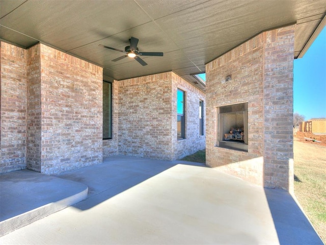 view of patio with an outdoor brick fireplace and ceiling fan