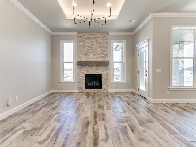 unfurnished living room featuring a fireplace, an inviting chandelier, ornamental molding, and light hardwood / wood-style flooring