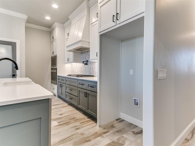 kitchen featuring white cabinetry, sink, stainless steel gas stovetop, custom exhaust hood, and ornamental molding