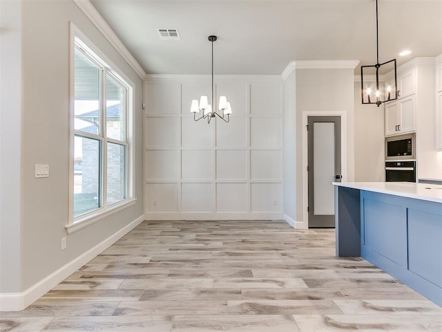 kitchen with a notable chandelier, decorative light fixtures, built in microwave, wall oven, and white cabinetry