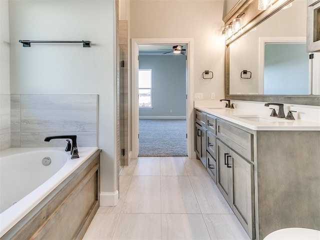 bathroom featuring tile patterned floors, vanity, ceiling fan, and tiled bath