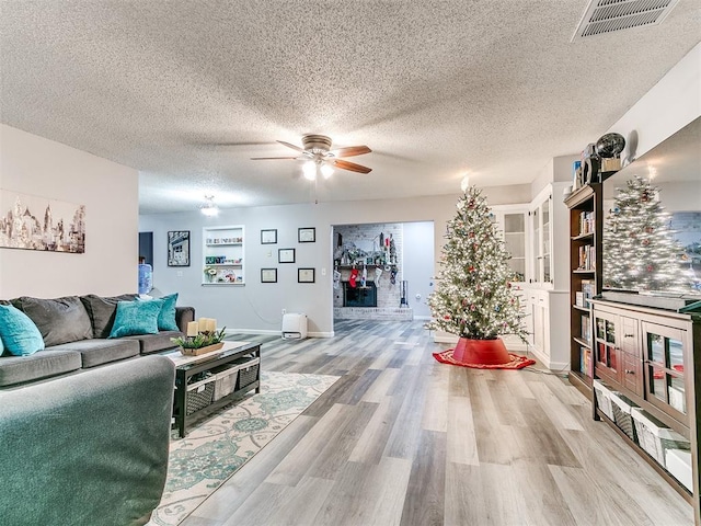 living room featuring a textured ceiling, light hardwood / wood-style flooring, and ceiling fan