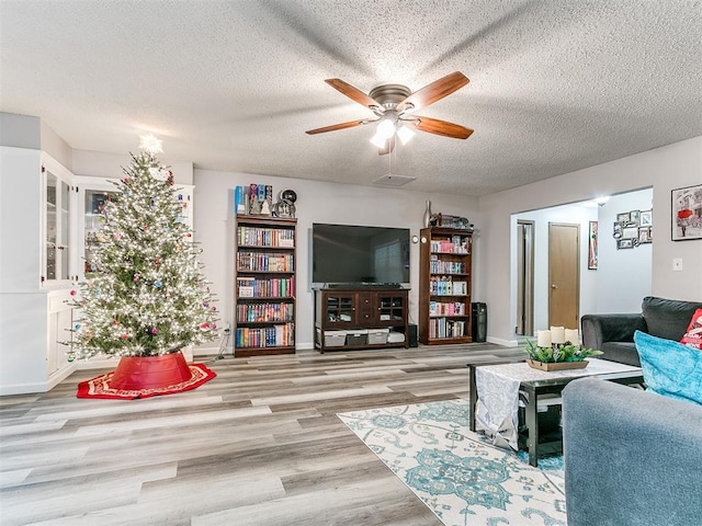 living room featuring ceiling fan, a textured ceiling, and light wood-type flooring