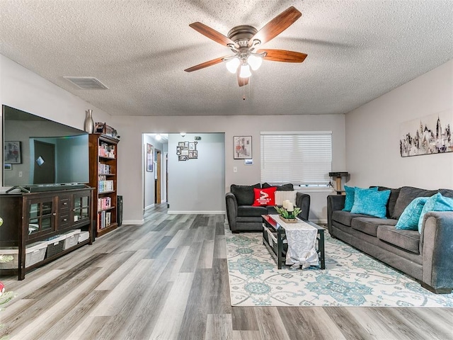 living room featuring a textured ceiling, light hardwood / wood-style floors, and ceiling fan