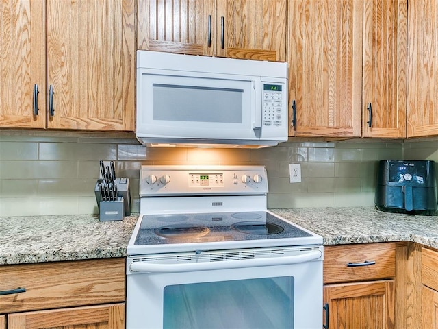 kitchen featuring light stone countertops, white appliances, and tasteful backsplash