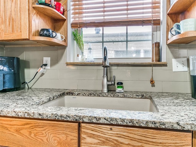 kitchen featuring light stone countertops, sink, and tasteful backsplash