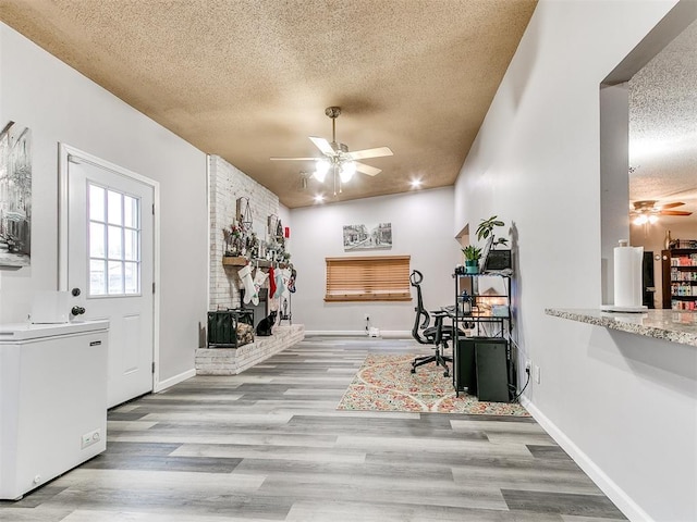 home office featuring a textured ceiling, light hardwood / wood-style floors, and ceiling fan