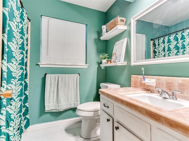 bathroom with vanity, backsplash, and toilet