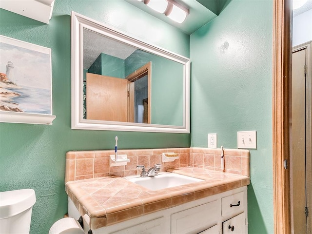 bathroom featuring vanity, tasteful backsplash, and toilet