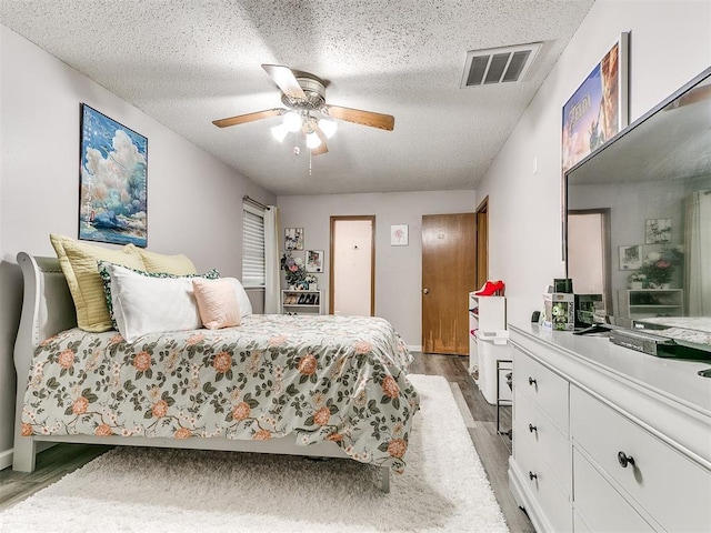 bedroom with ceiling fan, light hardwood / wood-style flooring, and a textured ceiling