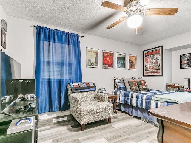 bedroom with ceiling fan, a textured ceiling, and hardwood / wood-style flooring