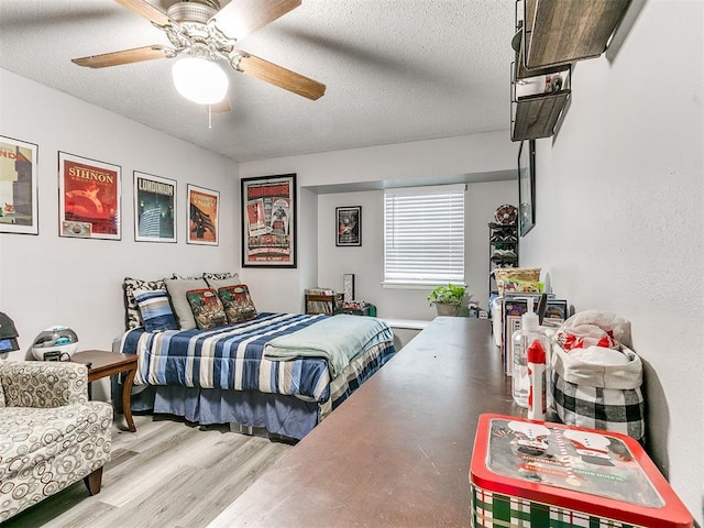 bedroom featuring ceiling fan, hardwood / wood-style floors, and a textured ceiling