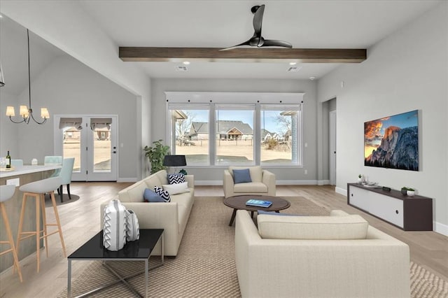 living room featuring beam ceiling, ceiling fan with notable chandelier, and light hardwood / wood-style floors