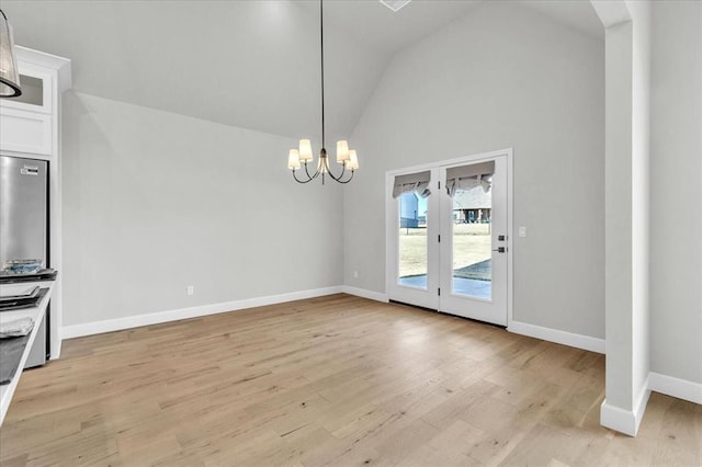 unfurnished dining area featuring light hardwood / wood-style flooring, high vaulted ceiling, and a notable chandelier