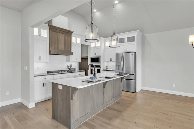 kitchen featuring white cabinets, an island with sink, decorative light fixtures, and appliances with stainless steel finishes