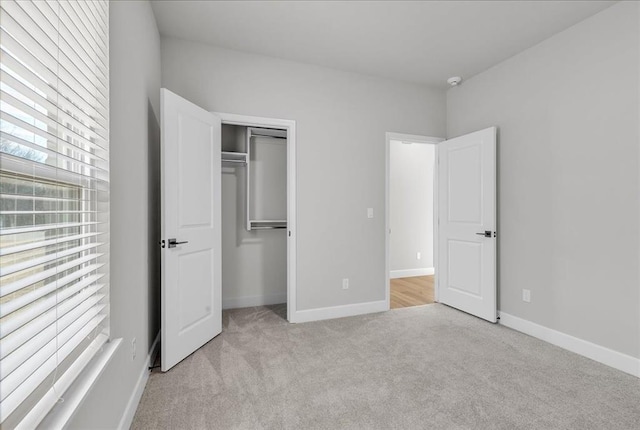 unfurnished bedroom with light carpet and a closet