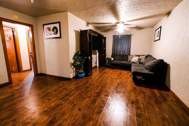 living room featuring ceiling fan, dark hardwood / wood-style flooring, and a textured ceiling