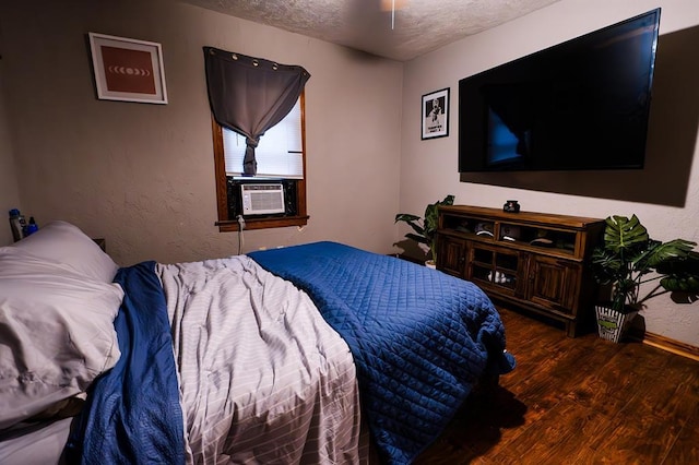 bedroom featuring cooling unit, a textured ceiling, and dark wood-type flooring