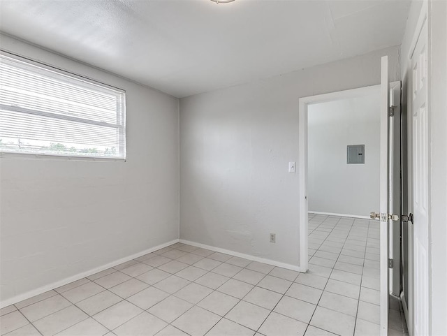 empty room with light tile patterned floors and electric panel