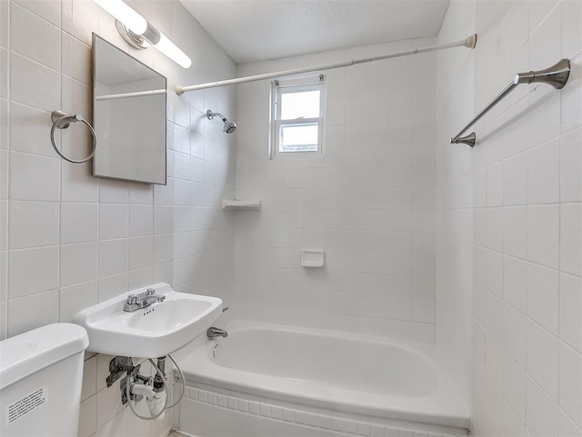 bathroom featuring tiled shower / bath, tile walls, and toilet