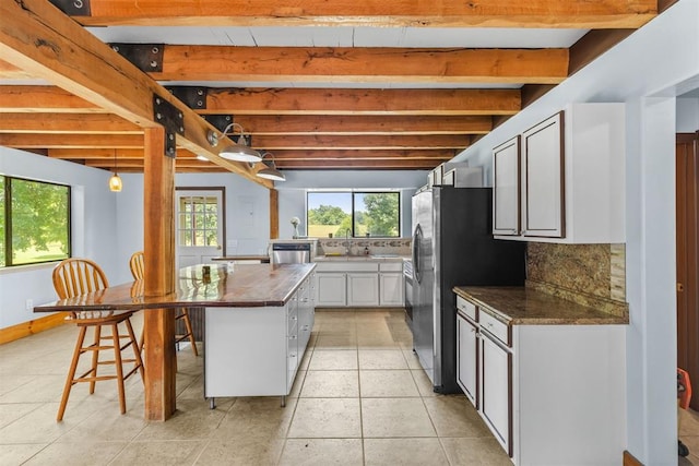 kitchen featuring beam ceiling, white cabinetry, a center island, wood counters, and decorative backsplash