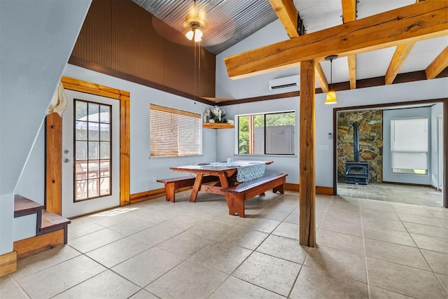 game room with a wall unit AC, a wood stove, light tile patterned flooring, and vaulted ceiling with beams