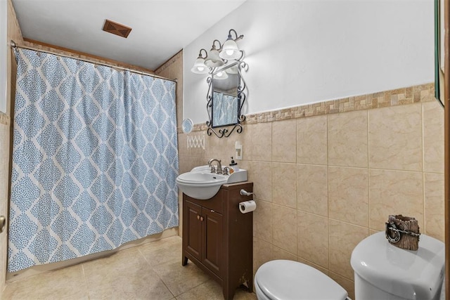 bathroom with a shower with curtain, tile patterned floors, toilet, vanity, and tile walls