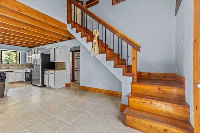 staircase featuring beam ceiling and tile patterned flooring