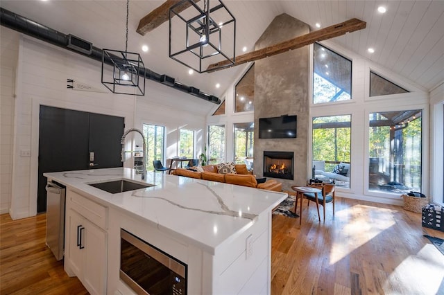 kitchen with stainless steel appliances, sink, decorative light fixtures, a center island with sink, and high vaulted ceiling