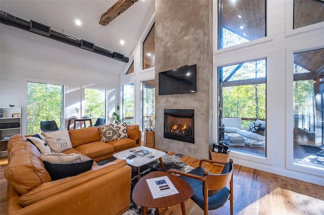 living room with a fireplace, hardwood / wood-style flooring, high vaulted ceiling, and beamed ceiling