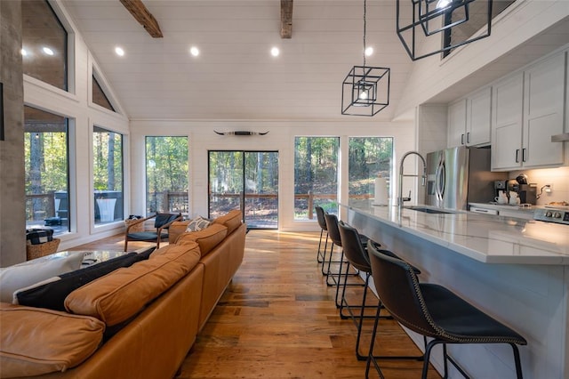 interior space featuring beam ceiling, light wood-type flooring, high vaulted ceiling, and plenty of natural light