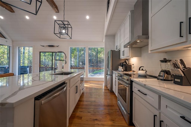 kitchen with appliances with stainless steel finishes, sink, white cabinetry, and wall chimney range hood