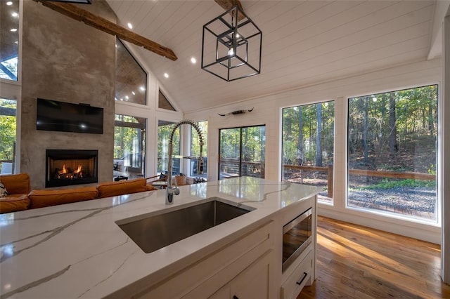 kitchen featuring stainless steel microwave, sink, light stone counters, pendant lighting, and a fireplace