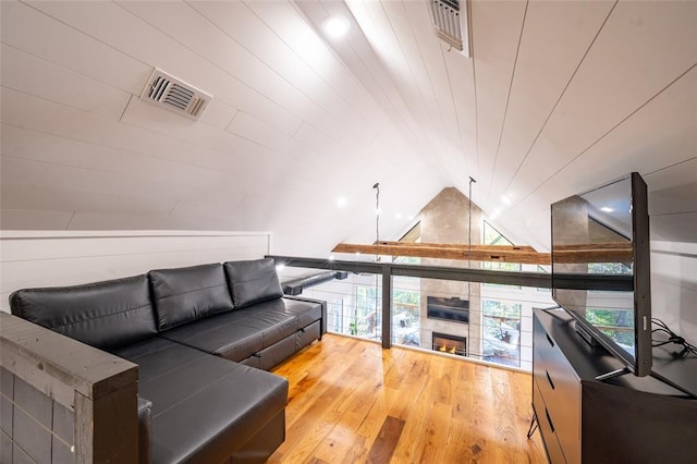 living room featuring lofted ceiling, wood-type flooring, and a tile fireplace