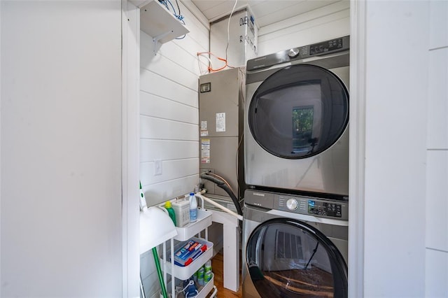 clothes washing area featuring wooden walls and stacked washer and clothes dryer