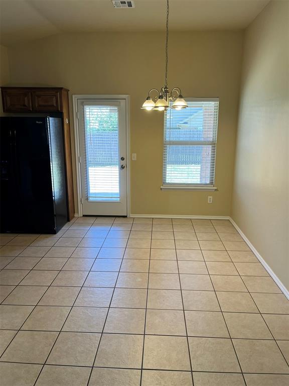 unfurnished dining area with plenty of natural light, light tile patterned floors, and a chandelier