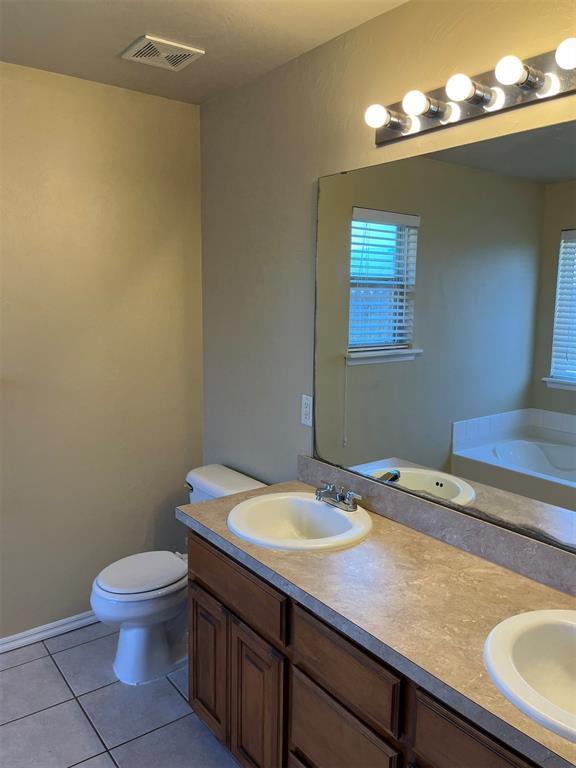 bathroom with tile patterned floors, vanity, toilet, and a tub