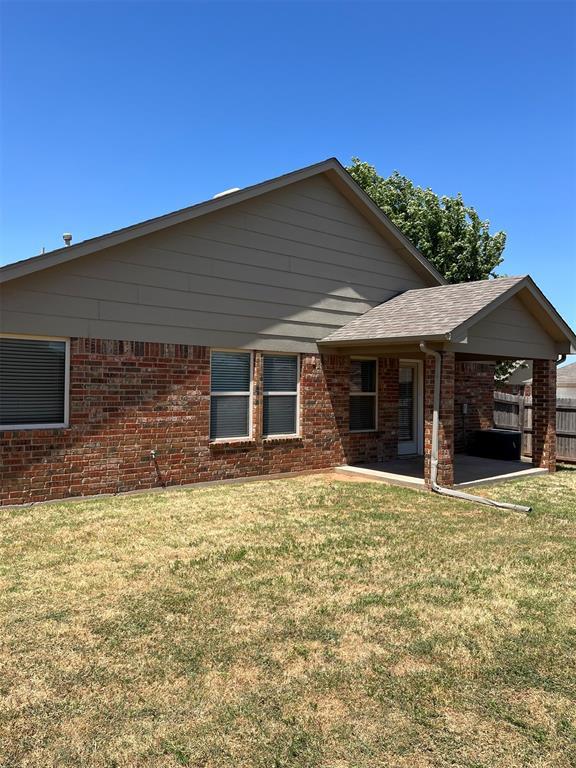 back of property with a yard and a carport