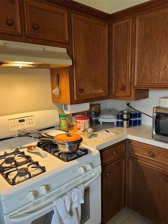 kitchen with white gas range oven and light tile patterned floors