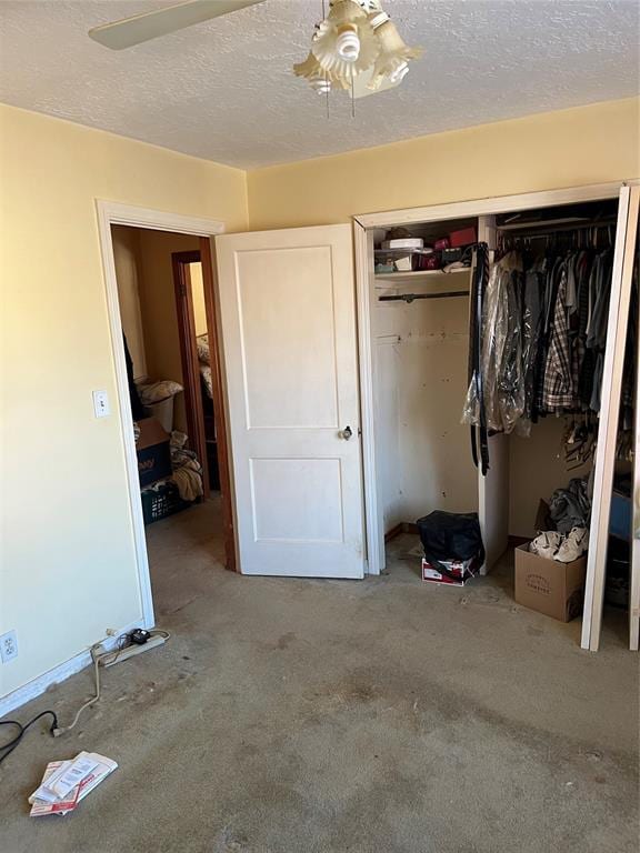 unfurnished bedroom featuring a textured ceiling, ceiling fan, a closet, and carpet flooring